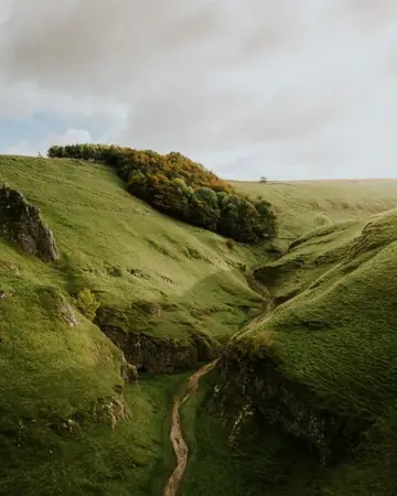 Un valle verde con un camino y nadie alrededor